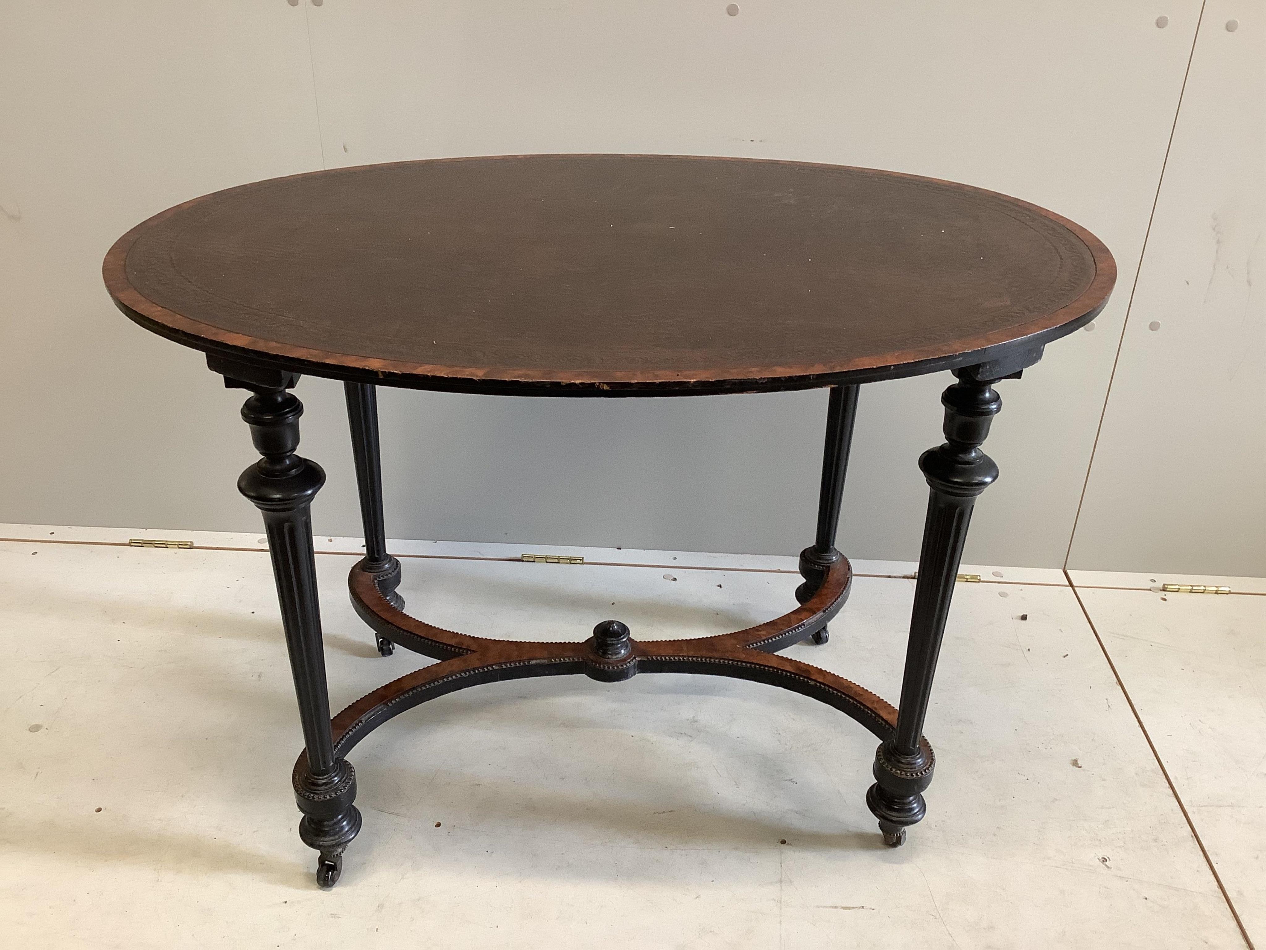 A Victorian oval ebonised and amboyna writing table, width 106cm, depth 75cm, height 73cm